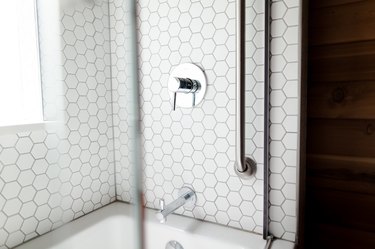 white hexagon tile shower, silver faucet and faucet handle, glass shower door