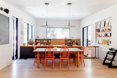 open dining room with orange chairs, pendant lamps, hardwood floors