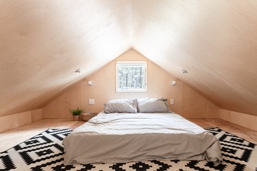 loft room with single bed and geometric rug, plywood walls