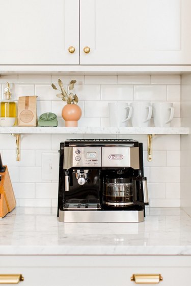 Farmhouse coffee bar with white subway tile, open marble shelf, and coffee maker
