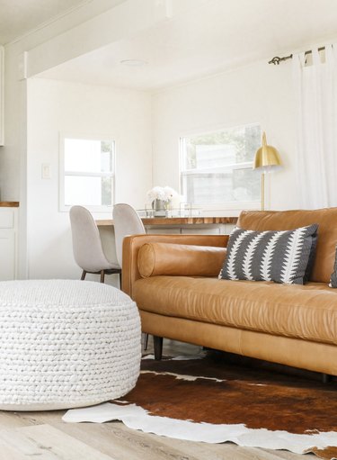 Brown leather sofa with textured area rug and organic foot stool