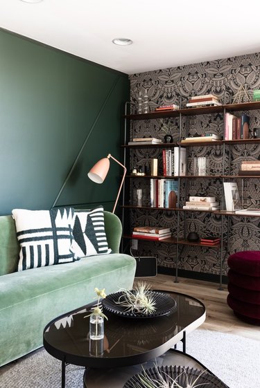 Home den/library with damask-like wallpaper and green velvet couch