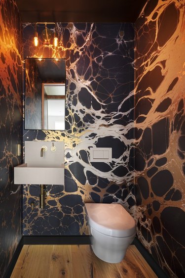 Powder room with bold patterned wallpaper in silver and black.