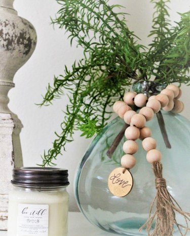 farmhouse DIY idea with wood bead garland on glass jar with greenery