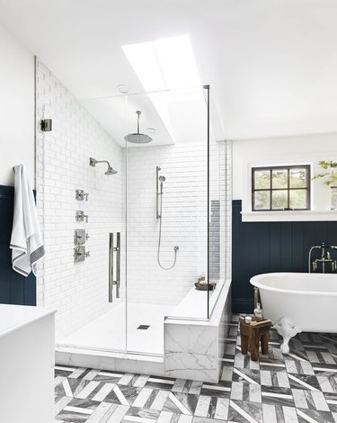 shower window idea with skylight in navy and white bathroom with clawfoot tub