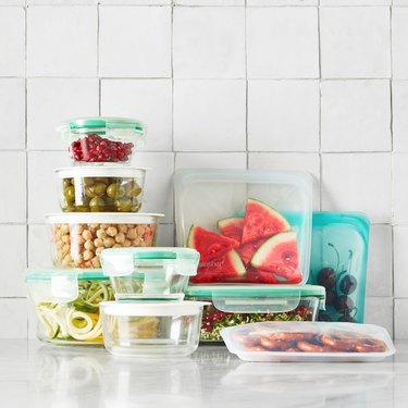 glass food storage containers stacked with reusable sandwich bags on a white counter