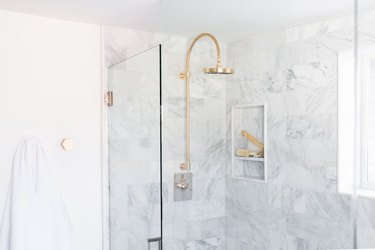 gold rain showerhead in marble shower
