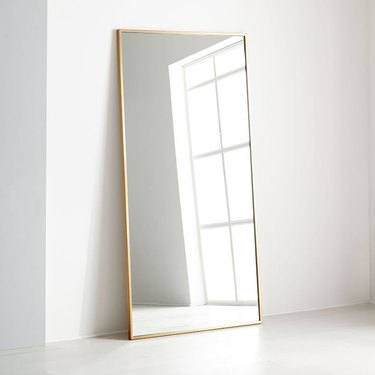 Oversized rectangular leaning floor mirror with thin brass border