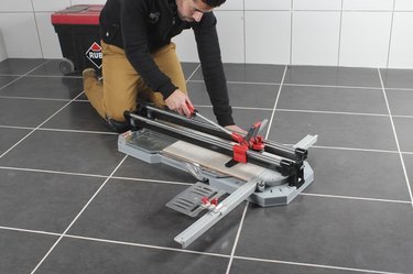 Cutting tile on the floor.