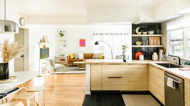 kitchen with view to living room, black tiled floor and walls, hardwood floors