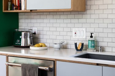 close up on white kitchen countertop with upper and lower cabinets and subway tile backsplash