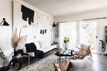 living room with French doors covered with a sheer curtain, concrete floors, white patterned rug