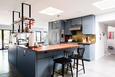 open kitchen with blue cabinets, wide windows, butcher block counter