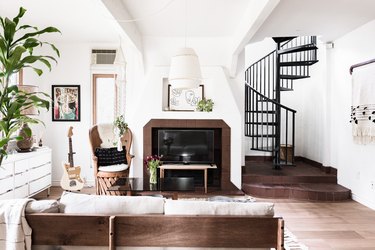 living room with fireplace, spiral staircase, large plant, guitar