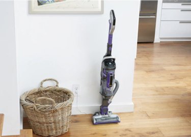 focus on vacuum and wicker basket against white wall