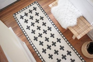 Natural jute rug painted with black patterns and design next to bench with sheepskin rug