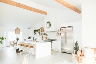 white kitchen with wood beams, large island, stainless steel fridge