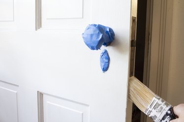 Blue painter's tape on door knob and hand painting side of door