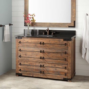 bathroom with wood vanity with black countertop