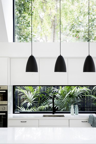all-white modern kitchen with black pendant lights and single-bowl sink