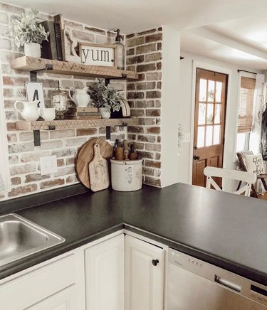 whitewashed brick backsplash with black countertop and white cabinets