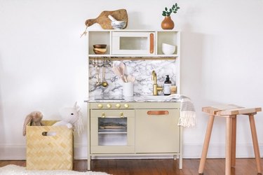 IKEA play kitchen with added marble paper and brass and leather handles.
