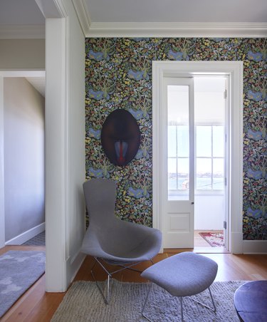 Hallway and seating area with patterned wall paper and modern chair