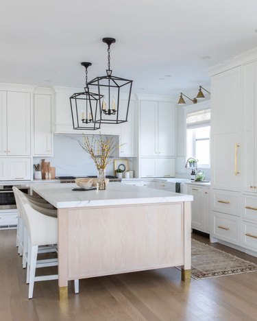 white kitchen with light wood island and brass hardware