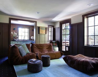 Family room with brown furniture, wood paneling, and turquoise carpet