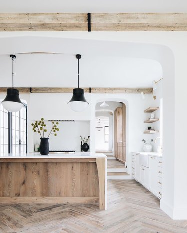 white wood and black kitchen with rustic wood island and herringbone floors
