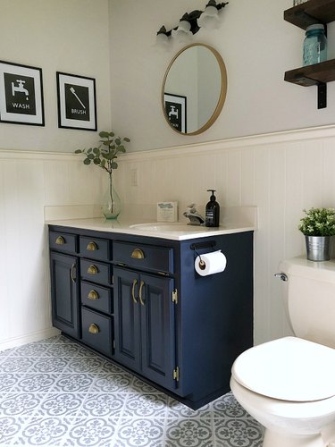 Navy blue bathroom cabinets with cement tile floor and wainscoting