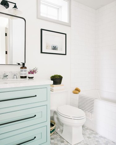 Mint bathroom cabinets in white bathroom with black hardware