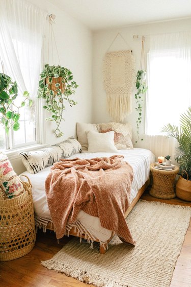 Boho bedroom with hanging plants and layered bedding