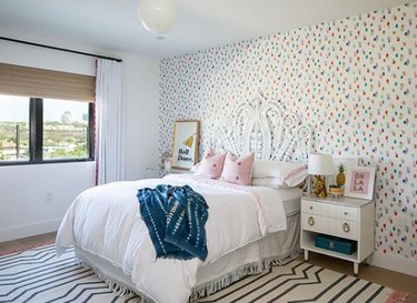 boho girls room with white rattan bed and polka dot wallpaper