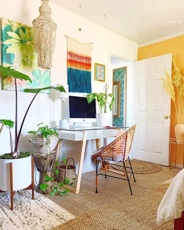 Boho office with rattan chair and multicolored fiber wall hanging