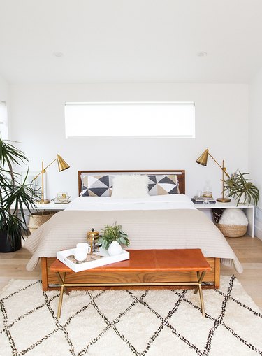 midcentury modern style bedroom with white walls and leather accent bench and area rug