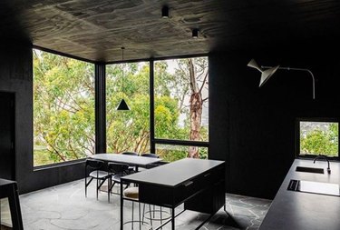 moody design with dark kitchen floors made of large stone slab and contrasting grout and black walls