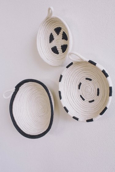 Three DIY cotton rope bowls hung on wall painted in black and white patterns