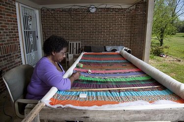 woman sitting in front of quilt she is working on