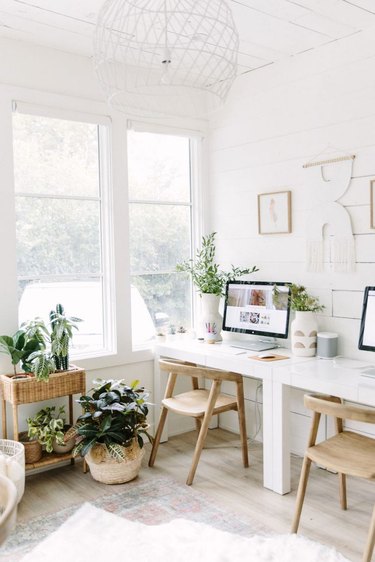 Boho office with natural sunlight, large windows, and white walls