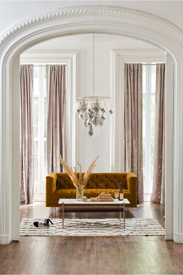 elegant art deco living room with mustard sofa and large droplet chandelier