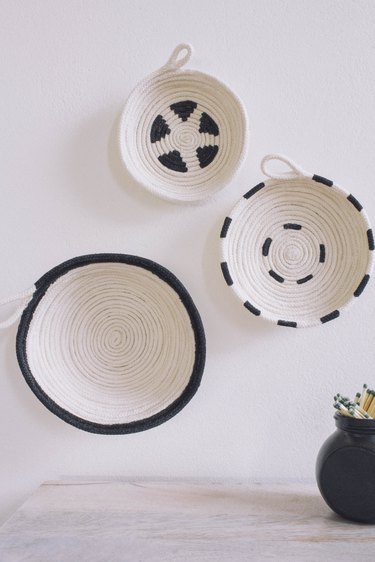 Three DIY cotton rope bowls hung on wall painted in black and white patterns