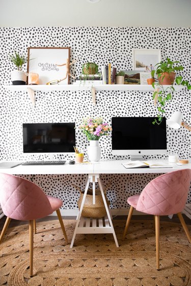 Boho office with black and white polka dot wallpaper and pink chairs