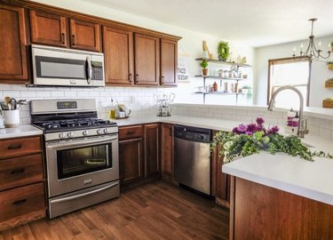 Walnut craftsman kitchen cabinets with matching wood floor and white subway tile backsplash