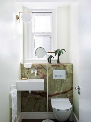 small bathroom with backlit panels of red-streaked green onyx