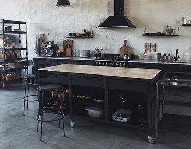black wooden industrial kitchen island with glossy butcher block top and metal barstools