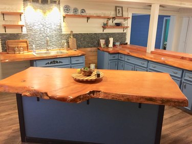 Live-edge wood slab in contemporary kitchen with blue cabinetry and wood floors