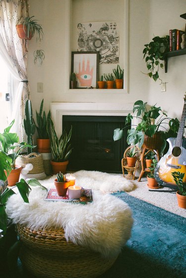 Boho apartment decor in living room with faux fur rugs, plants, and abstract artwork