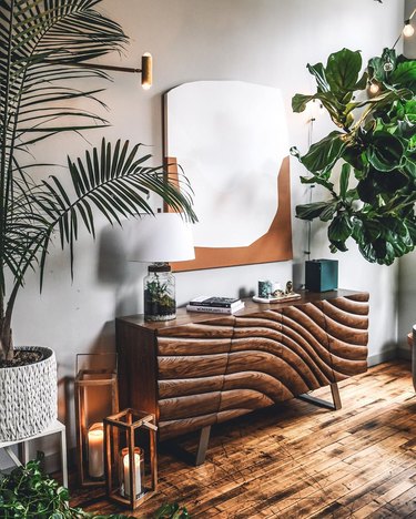 Boho apartment decor with artistic wood sideboard, plants, and abstract wall art