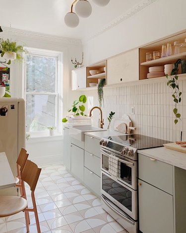 Boho apartment decor in galley kitchen with geometric floor tile and light green cabinets